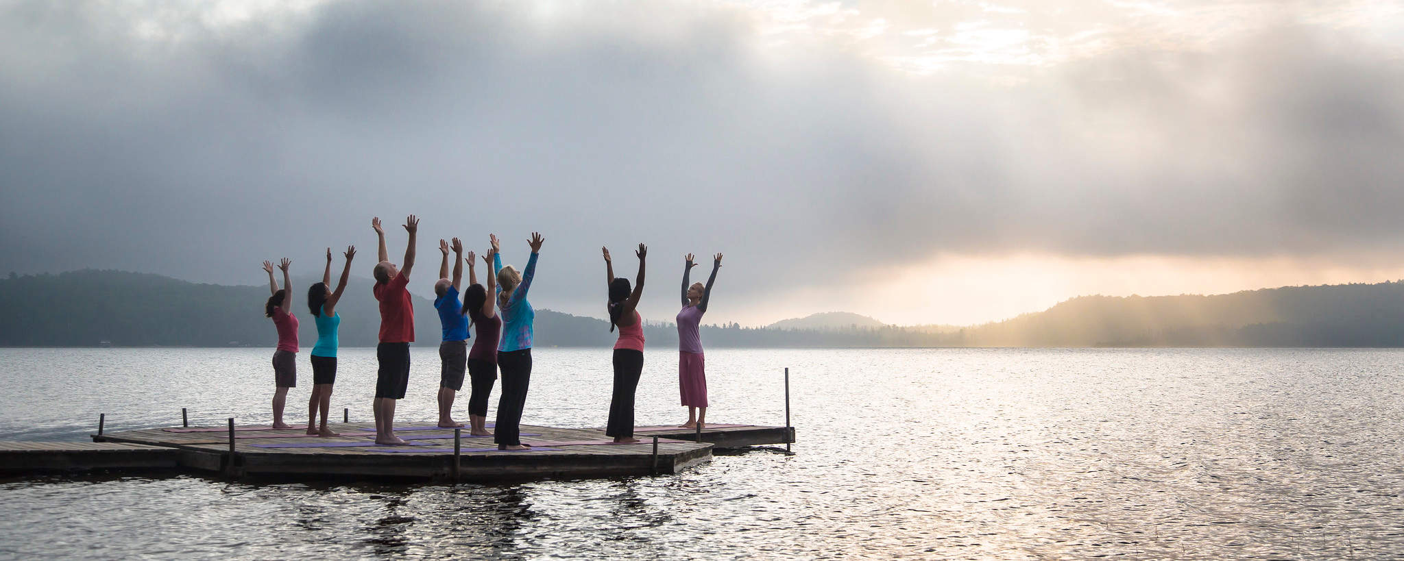 Group doing yoga on the dock in the sunset